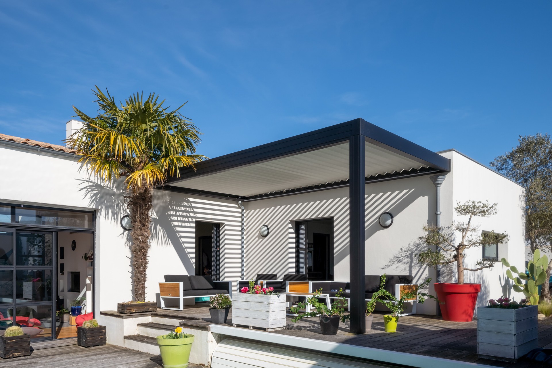 Trendy outdoor patio pergola. garden lounge, chairs, metal grill surrounded by landscaping